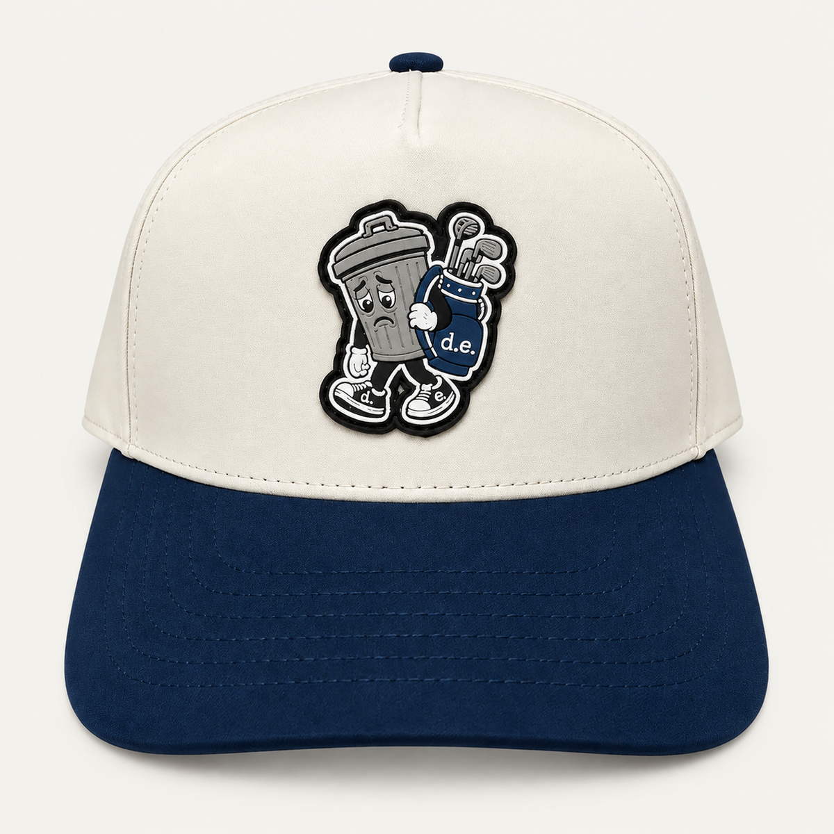 Cream and navy Basura trashcan golf hat with a trash can character carrying a golf bag, front view