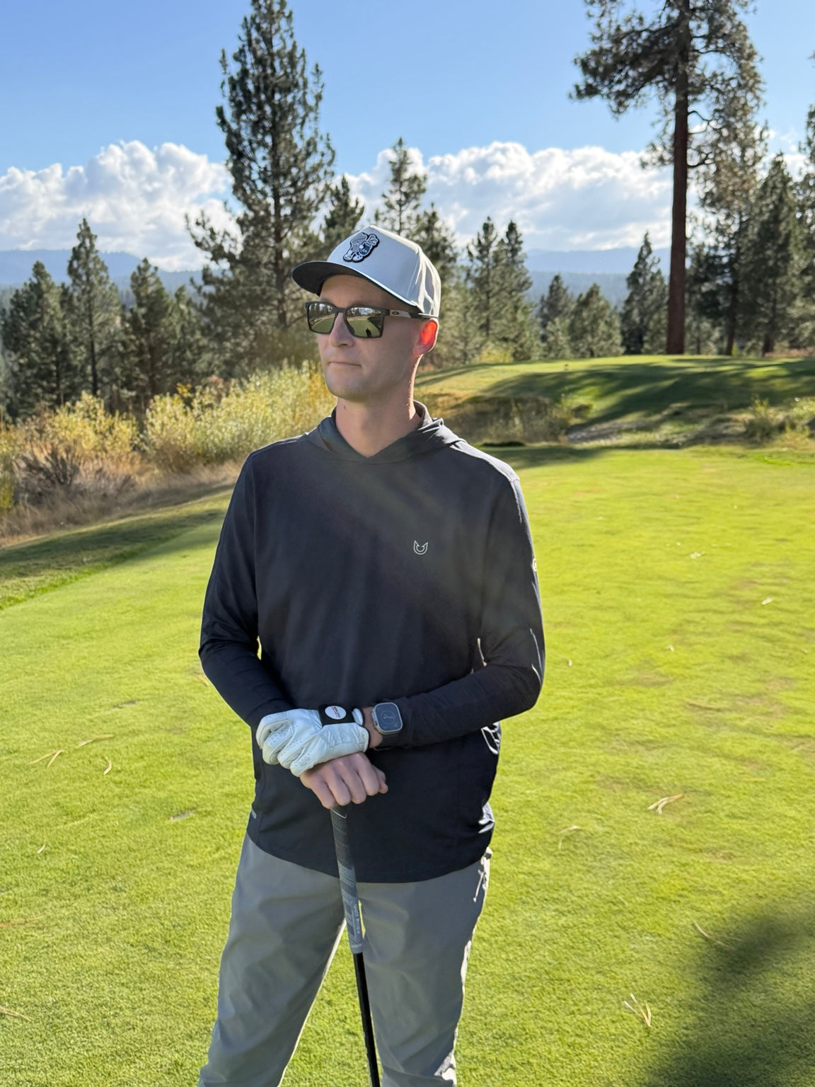 Golfer wearing a Basura hat on a sunlit golf course